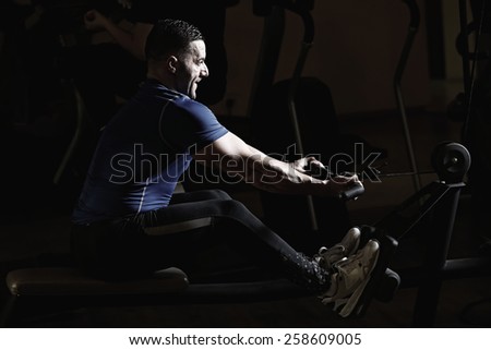 Sport, fitness, lifestyle, technology and people concept. Young man training in the gym