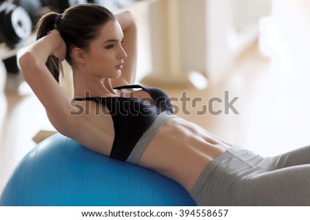 Woman exercising her abs on a Pilates ball. Natural light. Shallow DOF.