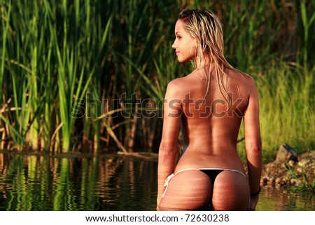 A blonde bikini model posing against a setting sun on a body of water