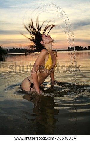 The beautiful bikini model posing against a setting sun on a body of water