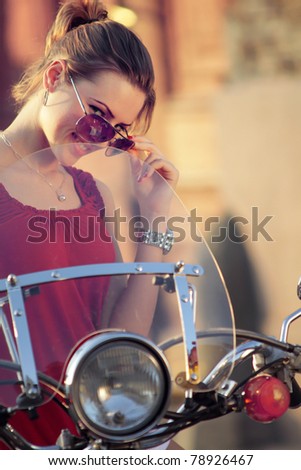 Portrait of smiling girl on scooter holding a helmet - Outdoor on street .Retro shot. Fashion art photo