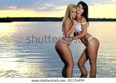 Beautiful girls posing in a warm water of a lake at sunset