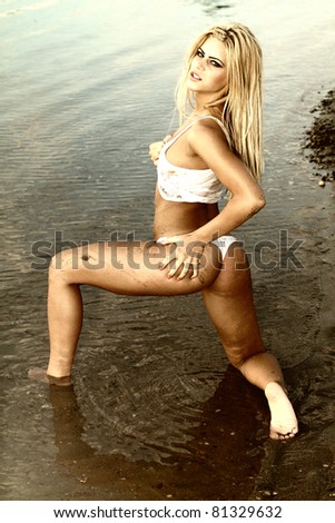 Blonde woman dressed in arab costume dancing in the warm water on a beautiful sunset