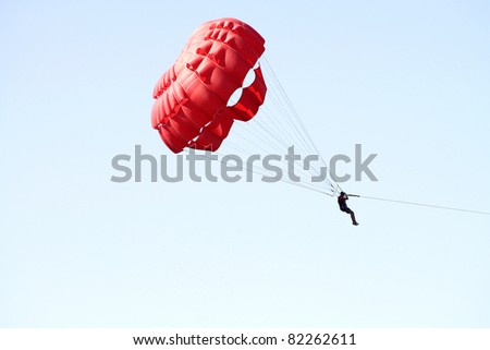 Man jumping with parachute over the blue sky