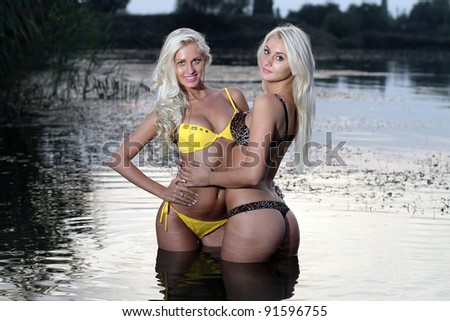 Two beautiful blonde girls in the warm water at sunset