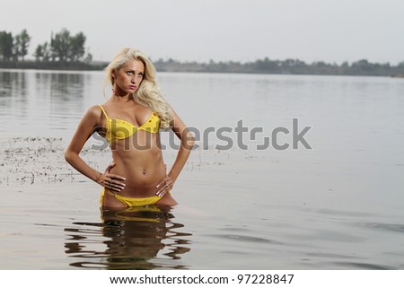 Beautiful blonde posing in the warm water at sunset