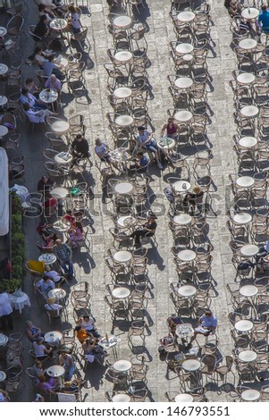 VENICE, ITALY - MAY 4: Tourists at San Marco square have a rest in one of many cafes with live music on May 4, 2012 in Venice, Italy. San Marco attracts more than 5 million visitors every year.