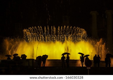 Abstract view: despite the heavy rain tourists enjoy wonderful Magic fountain of Montjuic light show at Plaza Espanya in Barcelona. Catalonia, Spain.