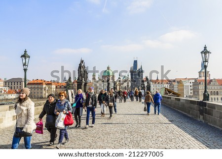 PRAGUE, CZECH REPUBLIC - MARCH 7, 2014: Tourists walking along Charles Bridge while sightseeing historical capital of the Czech Republic. Charles Bridge (Karluv most, 1357) - a famous historic bridge.