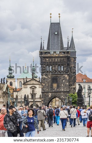 PRAGUE, CZECH REPUBLIC - JUNE 20, 2014: Tourists walking along Charles Bridge while sightseeing historical capital of the Czech Republic. Charles Bridge (Karluv most, 1357) - a famous historic bridge.