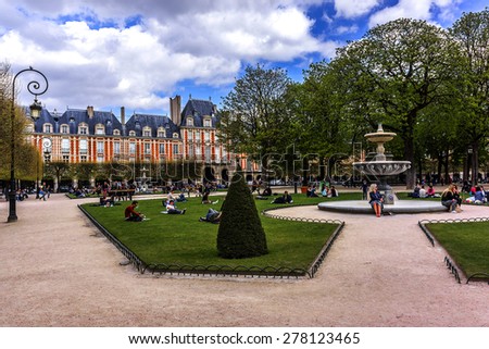 PARIS, FRANCE - APRIL 12, 2015: People relaxing on green lawns of famous Place des Vosges - oldest planned square in Paris, in Marais district. Place des Vosges was built by Henri IV from 1605 to 1612