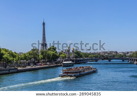 PARIS, FRANCE - JUNE 8, 2015: View of the Seine River with cruise tour boats. In Paris there are several boat tourist trips across the Seine to show tourists the sights of interest.