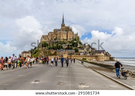 LE MONT SAINT MICHEL, FRANCE - JULY 19, 2012: Tourists visit Abbey Mont Saint-Michel (7th century) at rocky tidal island in Normandy - one of most visited tourist sites in France.