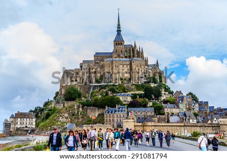 LE MONT SAINT MICHEL, FRANCE - JULY 19, 2012: Tourists visit Abbey Mont Saint-Michel (7th century) at rocky tidal island in Normandy - one of most visited tourist sites in France.