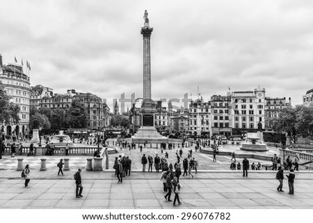 LONDON - MAY 30, 2013: Tourists visit Trafalgar Square in London. Trafalgar Square - the largest square in London, is often considered the heart of London. Black and white.