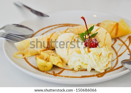 Vanilla ice cream and crepes stuffed with bananas topped with caramel and whipped cream.
