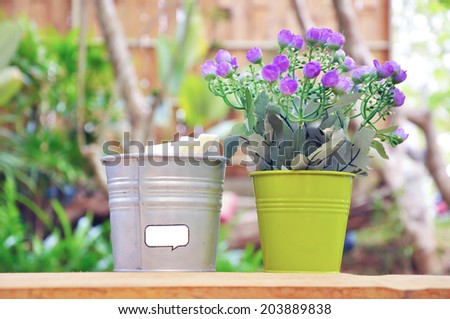 Tiny purple flowers in small bucket placed near the napkins bucket.