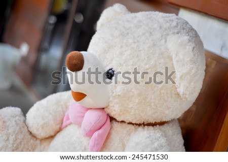 White teddy bear tied with pink scarf.