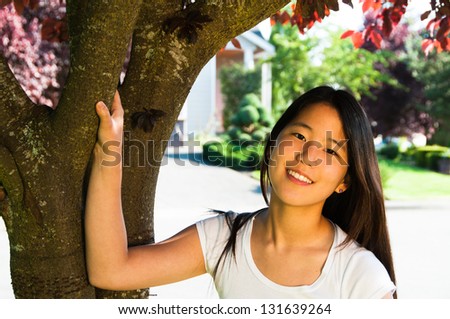 Portrait beautiful young ethnic Asian lady under blooming cherry tree