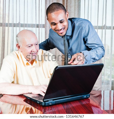 Young Black man and mature White male working on laptop computer