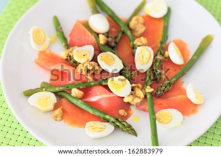 Smoked salmon with asparagus and quail eggs served in a dish with hazelnuts and mustard