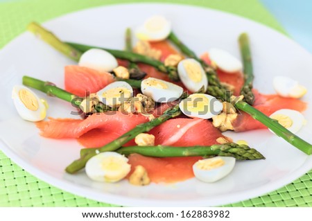 Smoked salmon with asparagus and quail eggs served in a dish with hazelnuts and mustard