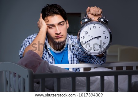 Young father dad sleeping while looking after newborn baby