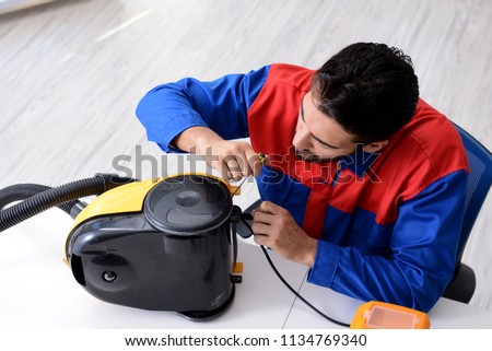 Man repairman repairing vacuum cleaner at service center