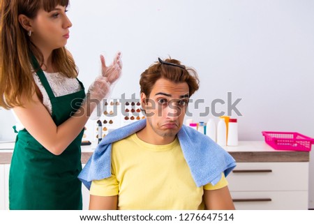 Woman hairdresser applying dye to man hair
