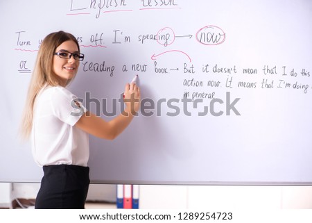 Young female english language teacher standing in front of the b