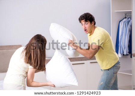 Wife and husband having pillow fight in bedroom