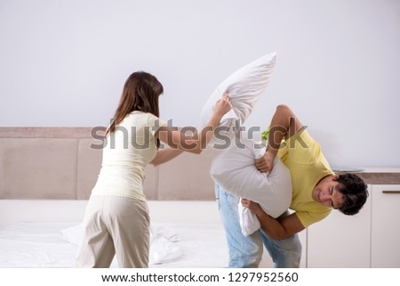 Wife and husband having pillow fight in bedroom