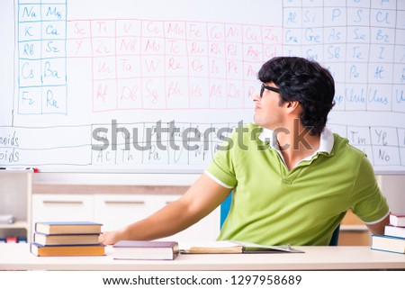 Young male student chemist in front of periodic table