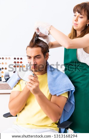 Woman hairdresser applying dye to man hair