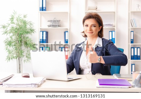 Middle-aged female employee sitting at the office