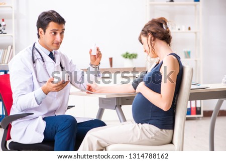 Young doctor checking pregnant woman\'s blood pressure