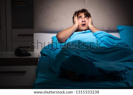 Young man scared in his bed having nightmares