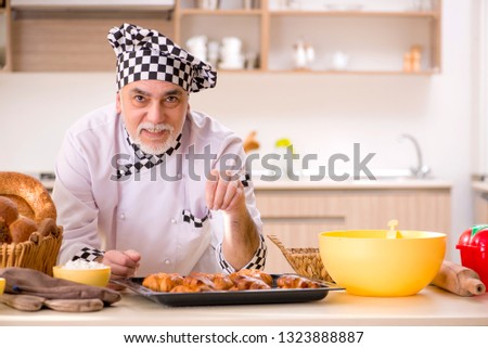 Old male baker working in the kitchen