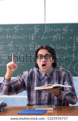 Young funny math teacher in front of chalkboard
