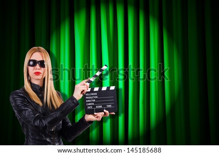 Girl with movie board against curtains