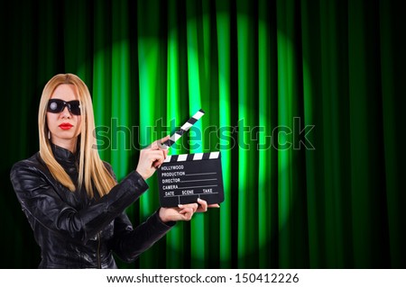 Girl with movie board against curtains
