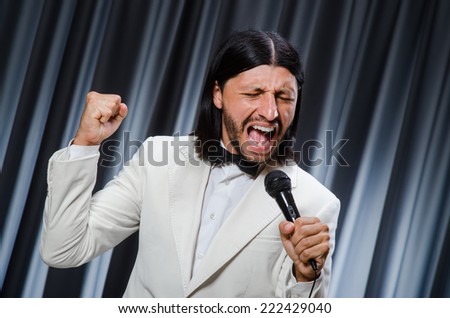 Man singing in front of curtain in karaoke concept