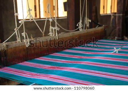 An old-style loom producing a colorful cloth
