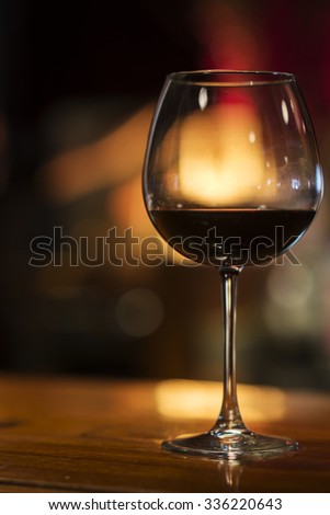 glass of red wine in cozy bar interior at night
