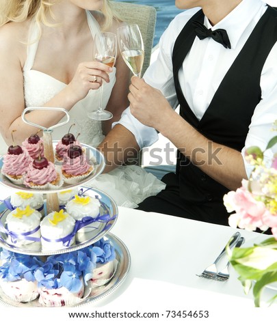 couple toasting at wedding with cakes on table