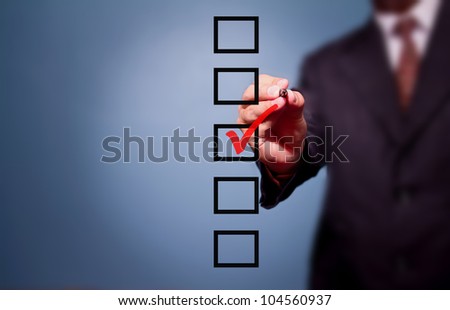 Young business man drawing a tick on a glass window in an office. Man choosing one of three options. On a gray background