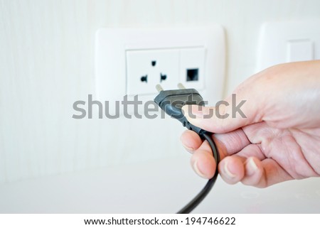 Electric cable with hand and Electrical Outlet on the Wall.