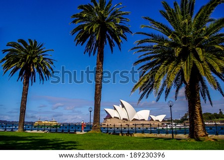 SYDNEY, AUSTRALIA - 10 October  2010: Far view of the Sydney Opera House from dawes point park with ferry crossing in a sunny day with trees as foreground. October 10, 2010 in Sydney, Australia.
