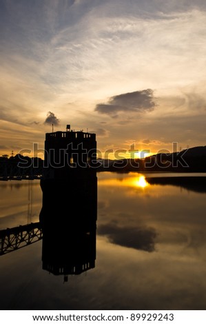 an architecture stands in the middle of water with perfect water reflection of the sky , cloud and the sunset