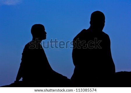 Silhouette of monk meditating at the top of the mountain